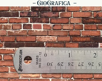 May include: A printed sheet featuring a realistic red brick wall pattern with white mortar lines. A silver Staedtler Mars 963 53-12 metal ruler is positioned across the bottom, showing a scale of 2 inches with 32nd-inch increments.