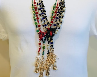 May include: Multi-strand necklace with red, green, black, and white beads. Each strand has a gold pendant with a religious figure.