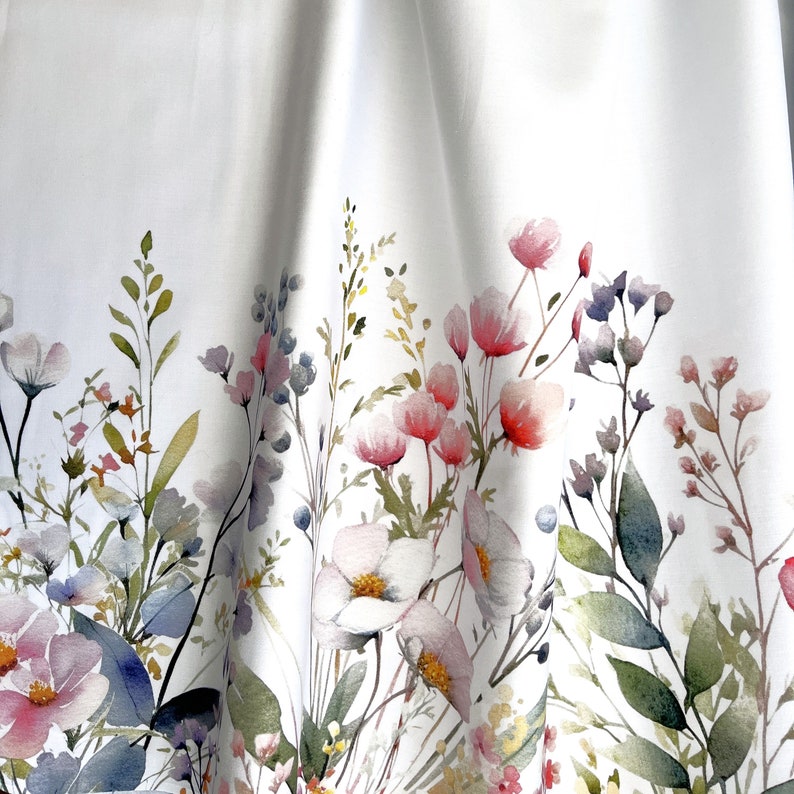 May include: White fabric with a watercolor floral print featuring pink, blue, and green flowers and leaves.