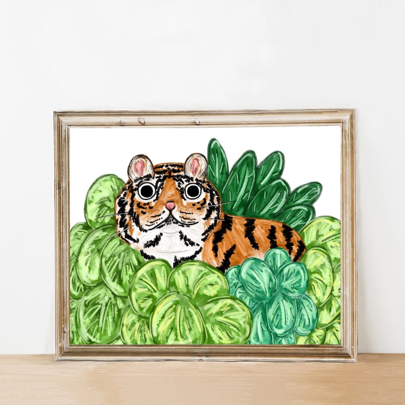Puede incluir: Una ilustraci&oacute;n de acuarela de un tigre asom&aacute;ndose desde detr&aacute;s de hojas verdes. El tigre tiene rayas naranjas y negras y ojos grandes y redondos.