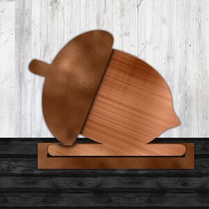 May include: A copper-colored acorn with a textured cap, sitting on a dark wood surface.