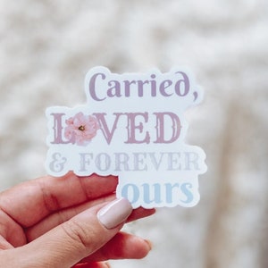 May include: A white sticker with pink floral accents and the text "Carried, Loved & Forever Ours".