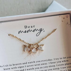 May include: Gold necklace with three clear cubic zirconia pendants, presented in a white gift box. The card inside reads "Dear mommy," with a heartfelt message below. A thoughtful gift.