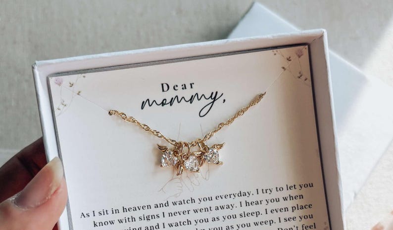 May include: Gold necklace with three clear cubic zirconia pendants, presented in a white gift box. The card inside reads "Dear mommy," with a heartfelt message below. A thoughtful gift.