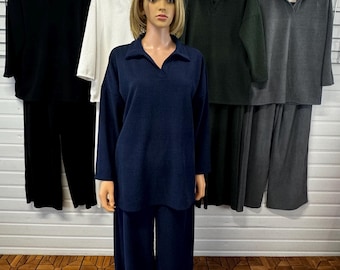 May include: Five long-sleeved collared shirts in different colors, including black, white, dark green, and gray. A mannequin is wearing a navy blue collared shirt and matching pants.