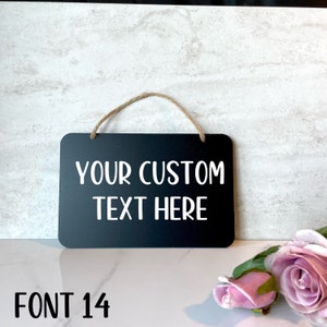 K&ouml;nnte beinhalten: Schwarzes Schild aus Schiefer mit einer Schnur zum Aufh&auml;ngen. Das Schild tr&auml;gt die Aufschrift "YOUR CUSTOM TEXT HERE" in wei&szlig;er Schrift. Die Schriftgr&ouml;&szlig;e betr&auml;gt 14.