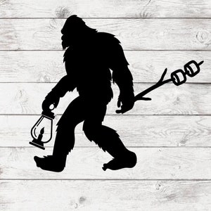 May include: A black silhouette of a Bigfoot holding a lantern in one hand and a stick with marshmallows on the other.