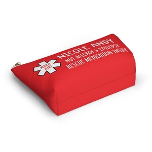 May include: Red zippered pouch with white text that reads "Nicole Andy Nut Allergy & Epilepsy Rescue Medication Inside". A red medical alert symbol with a white star is on the left side of the pouch.