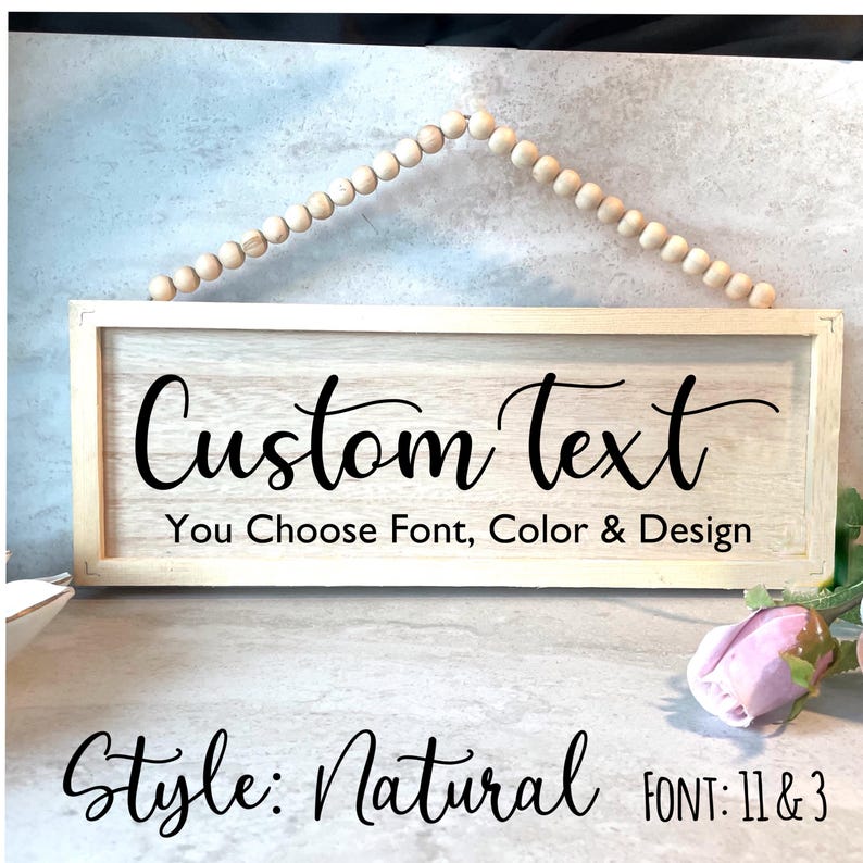 May include: A rectangular wooden sign with the words "Custom Text" in black script. The sign also says "You Choose Font, Color & Design". The sign is in a natural style and is suspended by a beaded string.