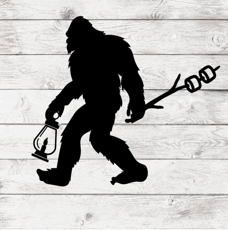 May include: A black silhouette of a Bigfoot holding a lantern in one hand and a stick with marshmallows on the other.