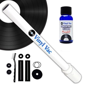 Może przedstawiać: Zestaw do czyszczenia płyt winylowych Vinyl Vac z białą rurką próżniową, czarnymi szczotkami do czyszczenia i butelką koncentratu do czyszczenia. Butelka jest niebieska z białym tekstem, który brzmi "Vinyl Vac Concentrate Cleaner Powerful! Record Cleaning Solution (1 oz)"