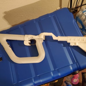 May include: A white plastic VR gun accessory for a video game console. The gun has a handle, a barrel, and a stock.