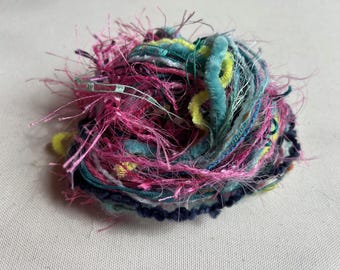May include: A ball of colourful yarn with pink, blue, green, and yellow strands. The yarn is fluffy and textured.