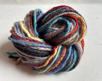 May include: A skein of colorful yarn with a mix of brown, blue, red, yellow, and white threads.