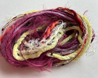 May include: A bundle of colourful yarn with shades of pink, yellow, orange, and white. The yarn is made of different textures, including fuzzy, smooth, and sparkly.