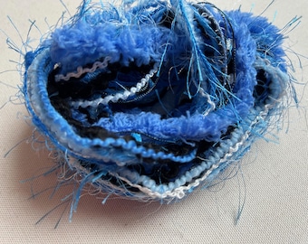 May include: A bundle of blue, white and black yarn with a fuzzy texture. The yarn is tangled and appears to be handmade.
