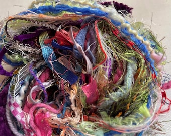 May include: A close-up of a pile of colorful yarn scraps, including pink, blue, green, and brown. The yarn is tangled and messy, creating a textured and abstract image.
