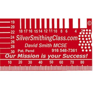 May include: Red metal ruler with a white scale and markings. The ruler has a white inscription that reads "SilverSmithingClass.com David Smith MCSE Pat. Pend 916 548-7361 Our Mission is your Success!"