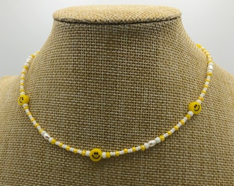 May include: A white and yellow beaded necklace with yellow smiley face charms.
