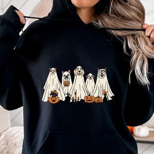 May include: Black hoodie with a graphic of five animals dressed as ghosts holding pumpkins and candy. The animals are a cat, a dog, a golden retriever, a husky, and a small dog. The graphic is in a vintage style.