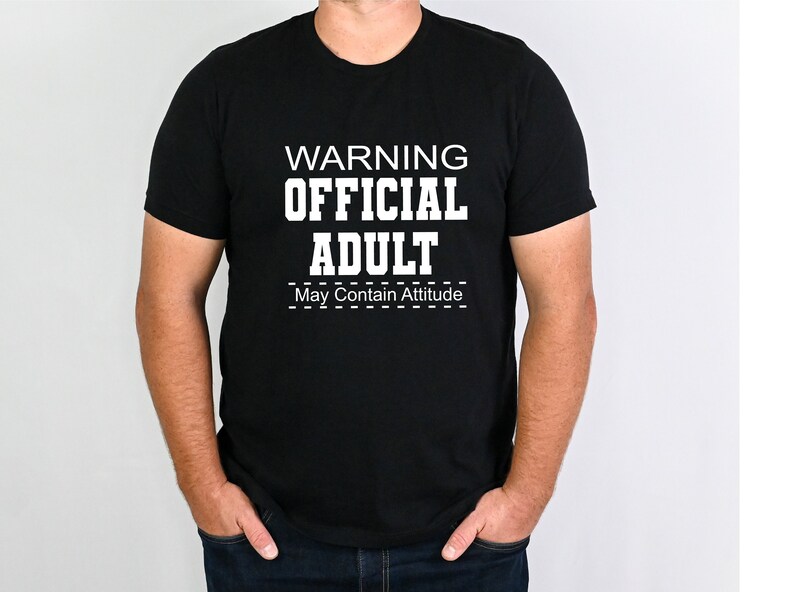 May include: Black t-shirt with white text that reads "WARNING OFFICIAL ADULT May Contain Attitude".