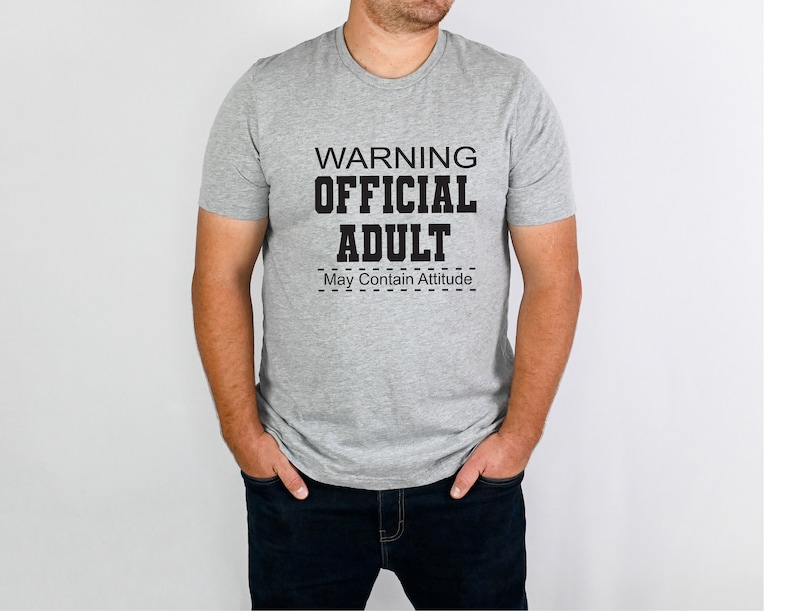 May include: A gray t-shirt with the text "WARNING OFFICIAL ADULT May Contain Attitude" printed in black.