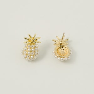 Op de afbeelding: Een paar gouden ananas oorbellen met witte parel accenten. De oorbellen worden van voren en achteren getoond.