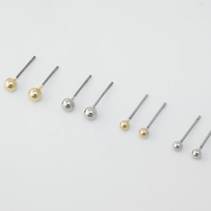 May include: A collection of small stud earrings with a ball design. The earrings are in gold and silver tones, with a simple post and ball design. The earrings are displayed on a white background.