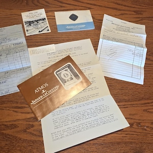 May include: A collection of vintage ephemera, including receipts, brochures, and a magazine. The items are arranged on a wooden surface. A brochure for "The Broadmoor" is visible, along with a "LIFE" magazine with the headline "LIFE TO THE MOON".