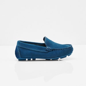 May include: A pair of blue suede loafers with a stitched seam around the edge of the shoe. The loafers have a rubber sole.