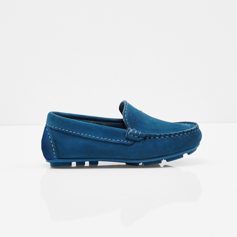 May include: A pair of blue suede loafers with a stitched seam around the edge of the shoe. The loafers have a rubber sole.