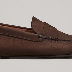 Peut inclure: Mocassins de conduite en cuir marron avec un d&eacute;tail de bride penny.