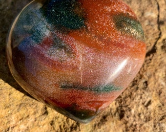 May include: A heart-shaped polished stone with red, green, and white swirling patterns.