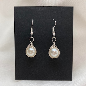 May include: A pair of silver wire wrapped earrings with white pearl drops.