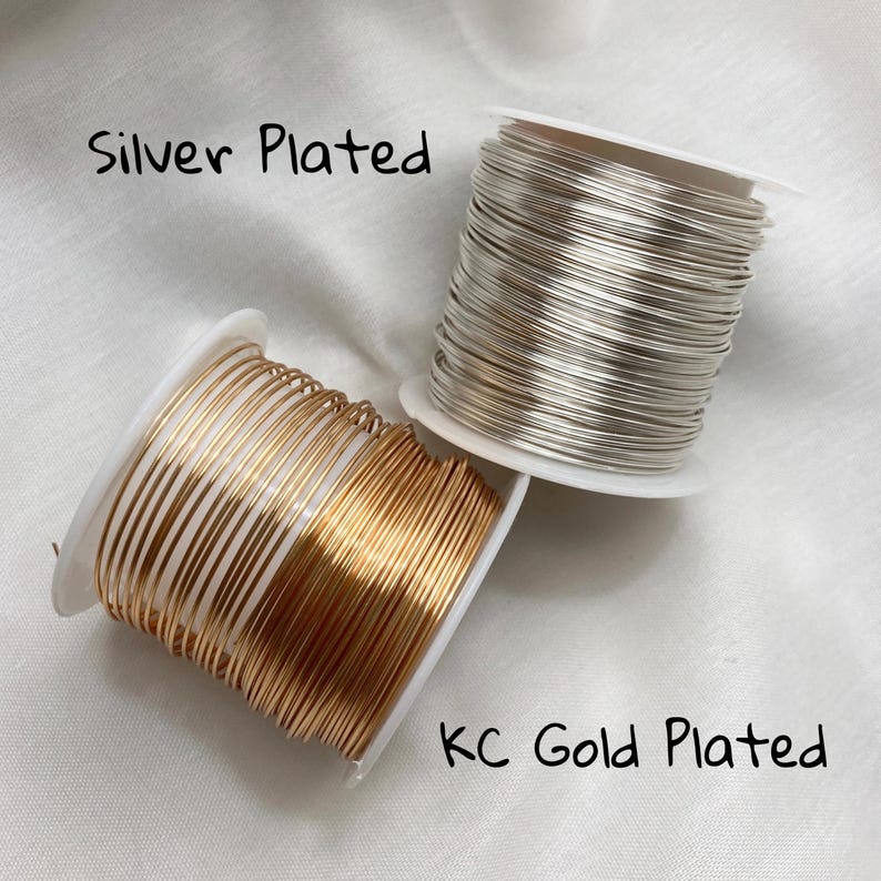 Puede incluir: Se muestran dos carretes de alambre, uno plateado y otro chapado en oro KC. El alambre plateado est&aacute; enrollado firmemente en un carrete blanco. El alambre dorado est&aacute; en un carrete similar. El texto de la imagen dice "Silver Plated" y "KC Gold Plated."