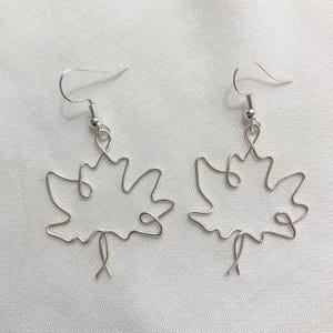 May include: A pair of silver wire earrings shaped like maple leaves.