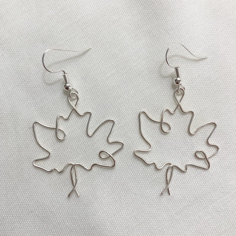 May include: A pair of silver wire earrings shaped like maple leaves.