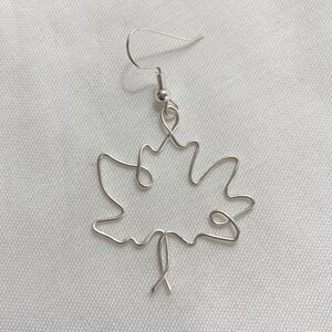 May include: Silver wire earrings shaped like a maple leaf.
