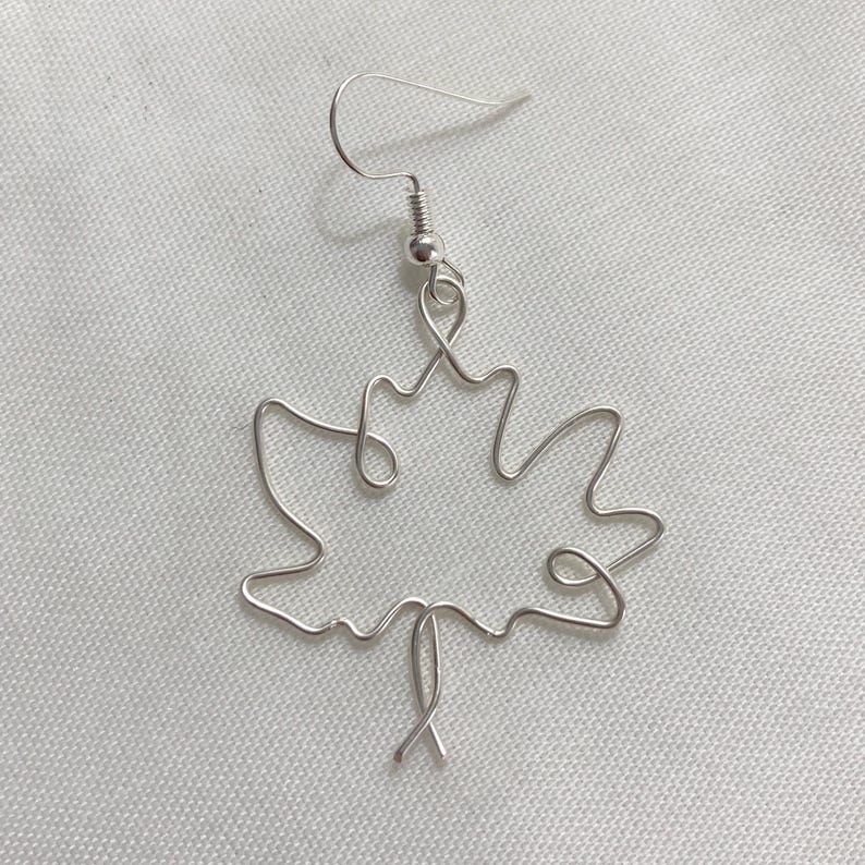 May include: Silver wire earrings shaped like a maple leaf.