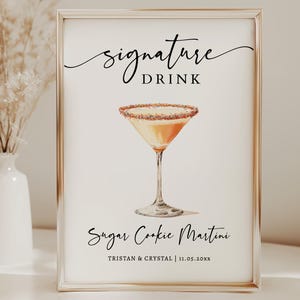 Op de afbeelding: Een ingelijst bord met de woorden "signature DRINK" in elegant schrift boven een aquarel illustratie van een Sugar Cookie Martini. De onderkant van het bord luidt "Sugar Cookie Martini" en de namen "Tristan & Crystal | 11.05.20xx".