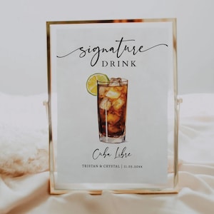 Puede incluir: Un letrero enmarcado con las palabras "signature DRINK" en escritura elegante. Debajo, una ilustración de acuarela de un cóctel Cuba Libre con hielo y una rodaja de lima. El letrero también incluye el texto "Cuba Libre" y nombres y una fecha.