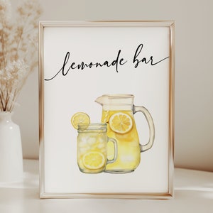 May include: A white sign with a gold frame that says "Lemonade Bar" in black cursive writing. A watercolor illustration of a pitcher and glass of lemonade with lemons is below the text.