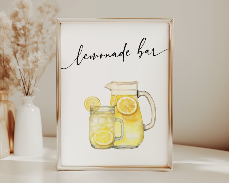 May include: A white sign with a gold frame that says "Lemonade Bar" in black cursive writing. A watercolor illustration of a pitcher and glass of lemonade with lemons is below the text.