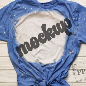 May include: A blue t-shirt with a white bleached design and the word "mockup" in black text.