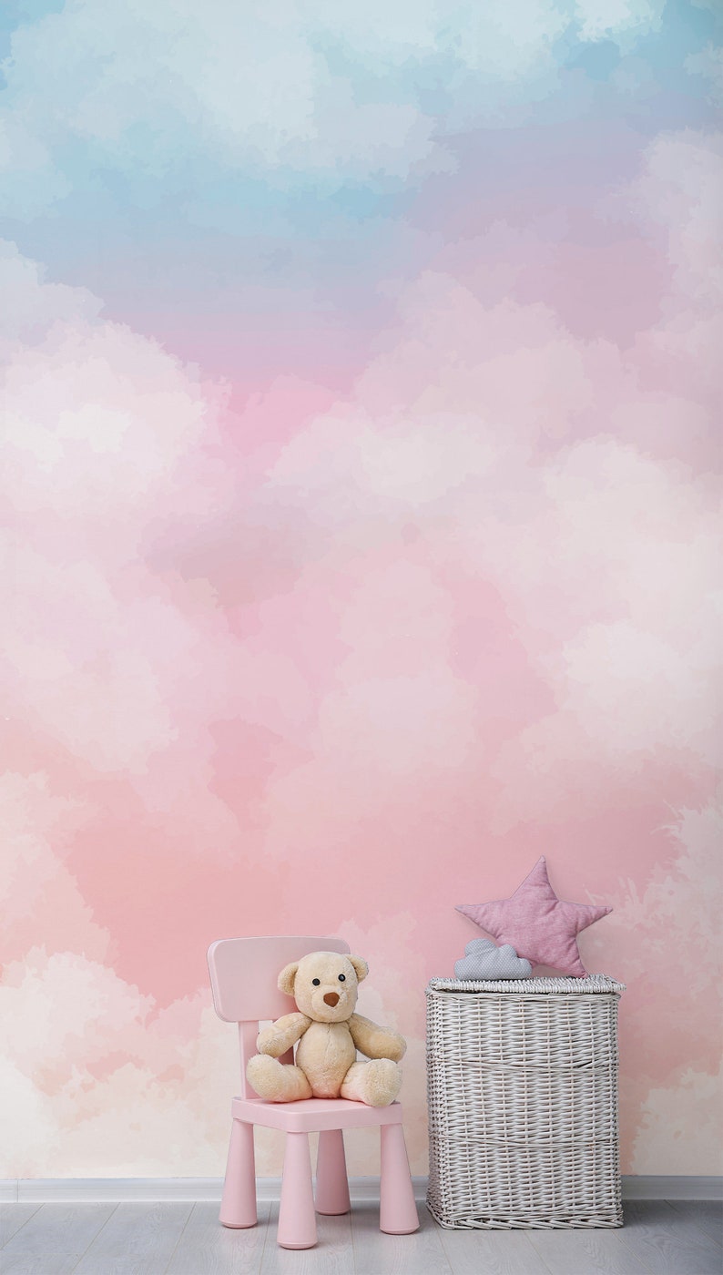 May include: A pink children's chair with a teddy bear sitting on it. A white wicker basket with a pink star-shaped pillow on top sits next to the chair. The background is a pink and blue watercolor-style wall with clouds.