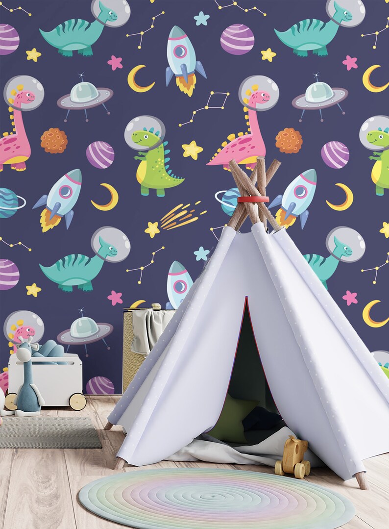 May include: A white teepee tent with a blue and white patterned background featuring dinosaurs, rockets, stars, and planets. The teepee is set up in a room with a wooden floor and a rainbow rug.