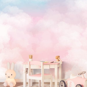 May include: A pink and blue watercolor cloud wall mural with a white desk and chair, a pink toy car, and a white bunny nightlight.