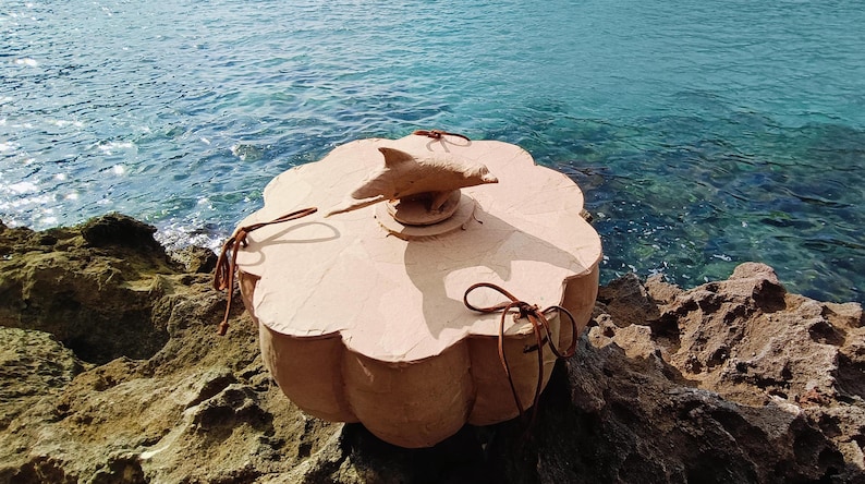 Close-up of a dolphin sea life symbol applied to the wooden lid of the SOUL SEA biodegradable water burial urn