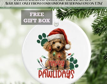 May include: A white ceramic Christmas ornament featuring a brown poodle wearing a red Santa hat and surrounded by colorful Christmas lights. The ornament reads "Happy Pawlidays".