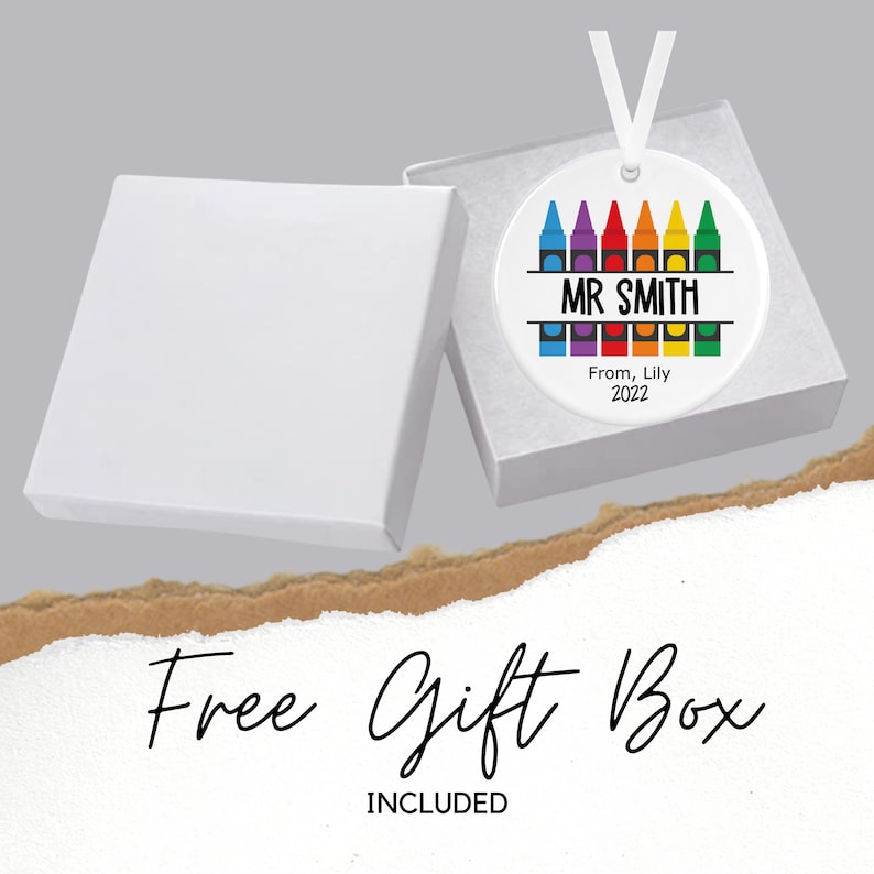 May include: A white ceramic bauble with a rainbow of crayons around the edge. The bauble says "MR SMITH" in black text and "From, Lily 2022" in smaller black text. The bauble comes in a white gift box.